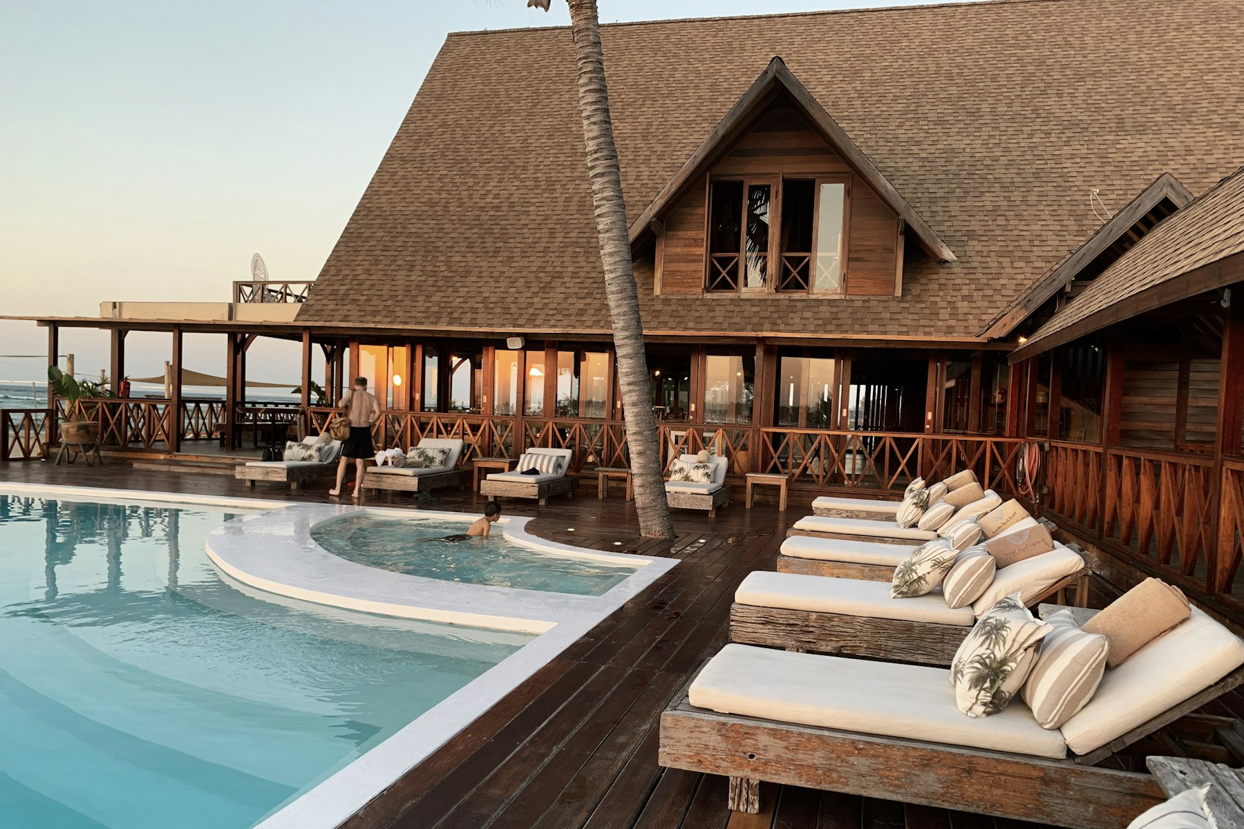 Beachfront boutique hotel with timber pavilion, pool and sun loungers at golden hour